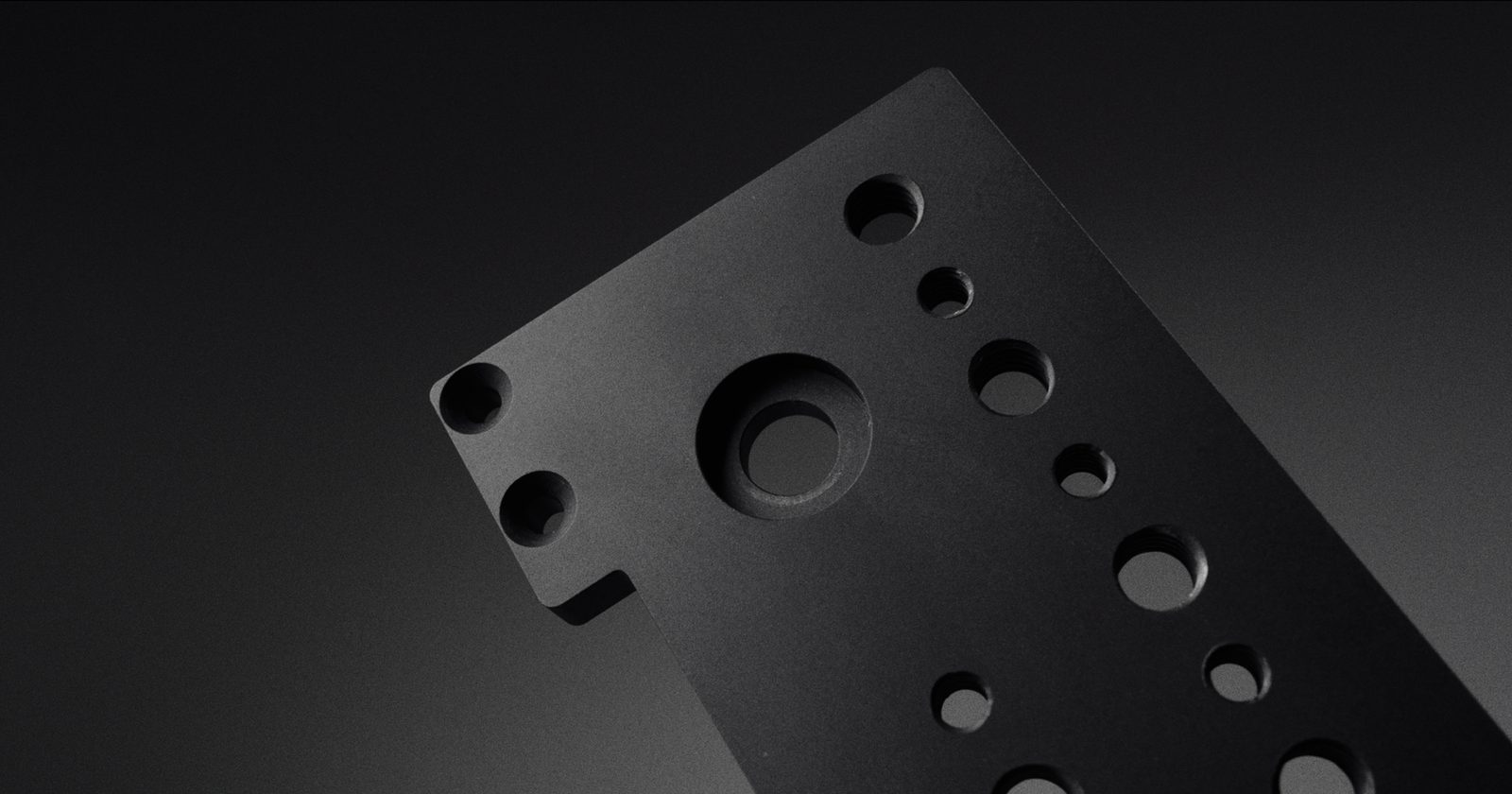 The base plate angled, showing the central tripod bore and the counterbored holes